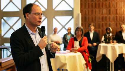 Geschäftsführer Andreas Schneider begrüßt mit einem Mikrofon in der Hand die Gäste bei der Weihnachtsfeier 2025 von Amalie Sieveking Krankenhaus, Residenz am Wiesenkamp, Feierabendhaus Volksdorf und Albertinen Kindertagesstätte Volksdorf auf dem Gesundheitscampus Volksdorf in Hamburg