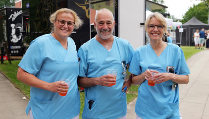 Drei Mitarbeitende in Funktionskleidung halten Getränke in den Händen und lächeln in die Kamera beim Sommerfest 2026 auf dem Gesundheitscampus Volksdorf des Evangelischen Amalie Sieveking Krankenhauses, der Residenz am Wiesenkamp, des Feierabendhauses Volksdorf und der Albertinen Kindertagesstätte Volksdorf. Drei Mitarbeitende in Funktionskleidung halten Getränke in den Händen und lächeln in die Kamera beim Sommerfest 2026 auf dem Gesundheitscampus Volksdorf des Evangelischen Amalie Sieveking Krankenhauses, der Residenz am Wiesenkamp, des Feierabendhauses Volksdorf und der Albertinen Kindertagesstätte Volksdorf.