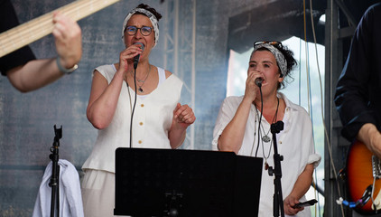 Zwei Sängerinnen singen in festlich weißer Kleidung auf der Konzertbühne während eines Konzerts beim Sommerfest 2026 auf dem Gesundheitscampus Volksdorf des Evangelischen Amalie Sieveking Krankenhauses, der Residenz am Wiesenkamp, des Feierabendhauses Volksdorf und der Albertinen Kindertagesstätte Volksdorf. Zwei Sängerinnen singen in festlich weißer Kleidung auf der Konzertbühne während eines Konzerts beim Sommerfest 2026 auf dem Gesundheitscampus Volksdorf des Evangelischen Amalie Sieveking Krankenhauses, der Residenz am Wiesenkamp, des Feierabendhauses Volksdorf und der Albertinen Kindertagesstätte Volksdorf.