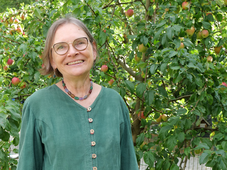Mirjam Ritz steht lächelnd vor einem Apfelbaum