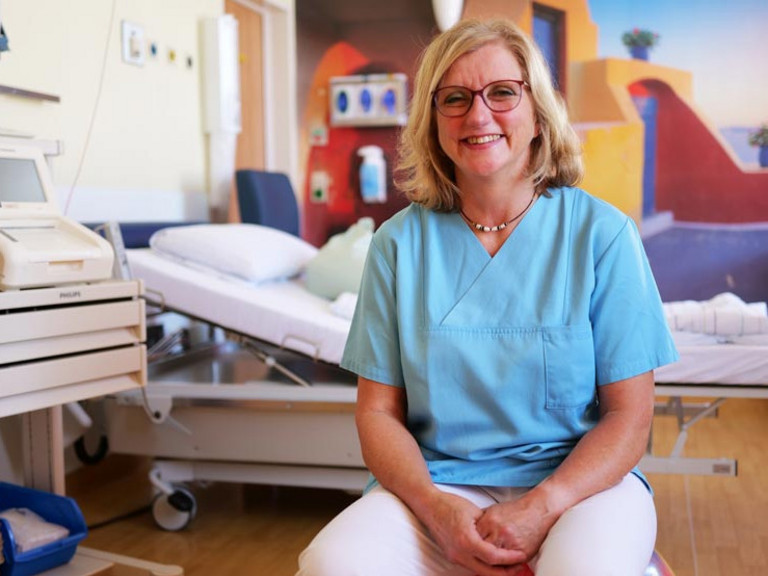 Kerstin Stehr-Archuth, Leitende Hebamme im Evangelischen Amalie Sieveking Krankenhaus, sitzt in einem Kreißsaal und blickt in die Kamera